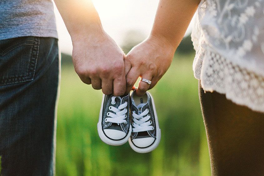 Man and Woman Holding Baby Shoes in Hands Man and Woman Holding Baby Shoes in Hands